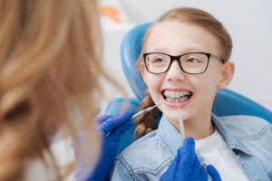 Positive smiley girl having her braces checked