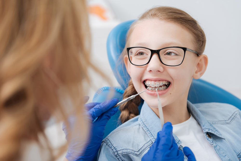 Positive smiley girl having her braces checked