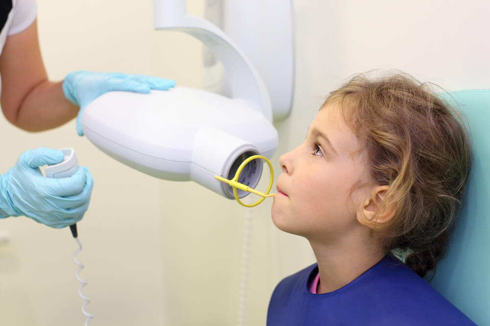 Dentist hands make jaw x-ray image for little girl in dental clinic